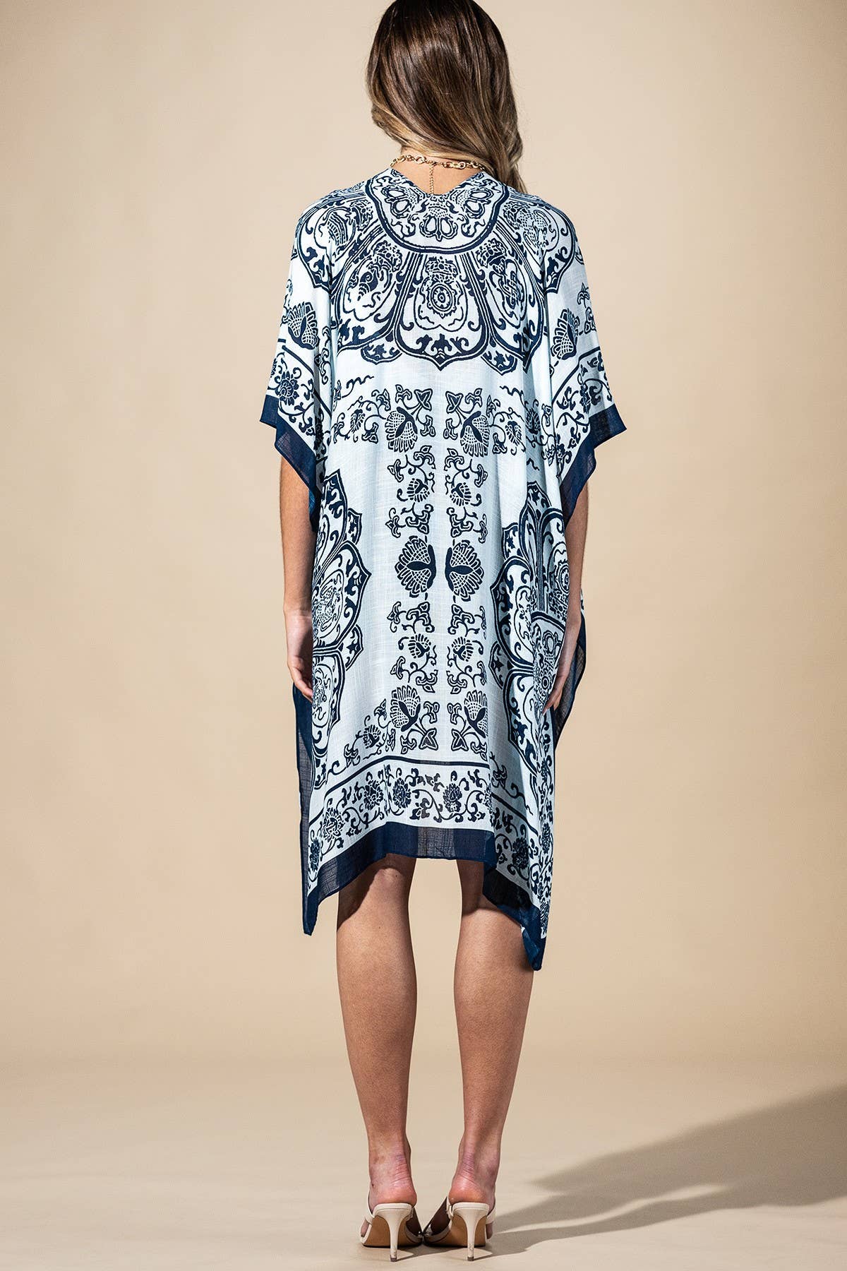 Woman wearing a blue and white patterned dress against a beige background