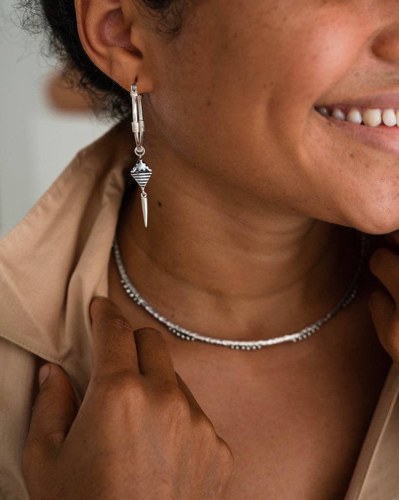 Close-up of a person wearing a silver earring and necklace.