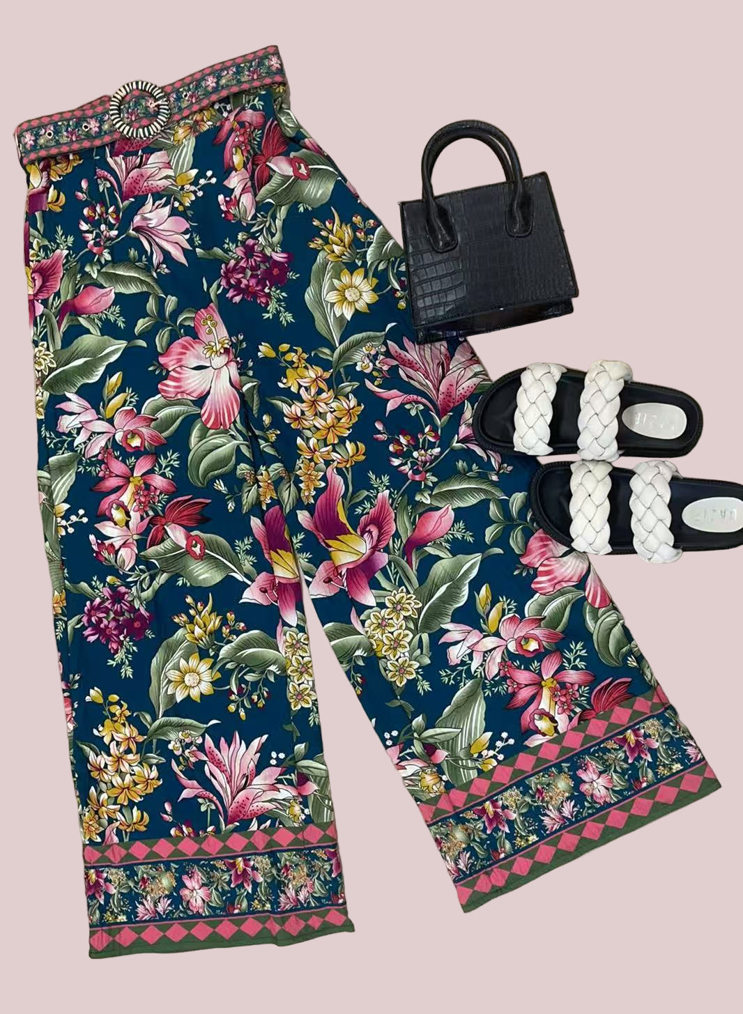 Floral pants with a black handbag and sandals on a wooden floor