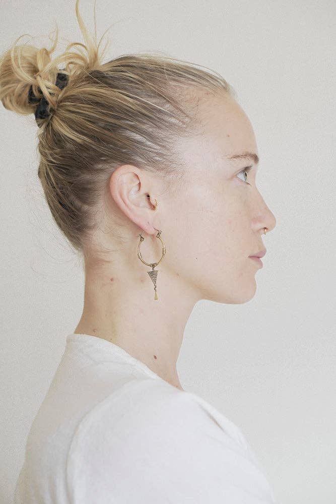 Side profile of a person wearing a hoop earring against a plain background