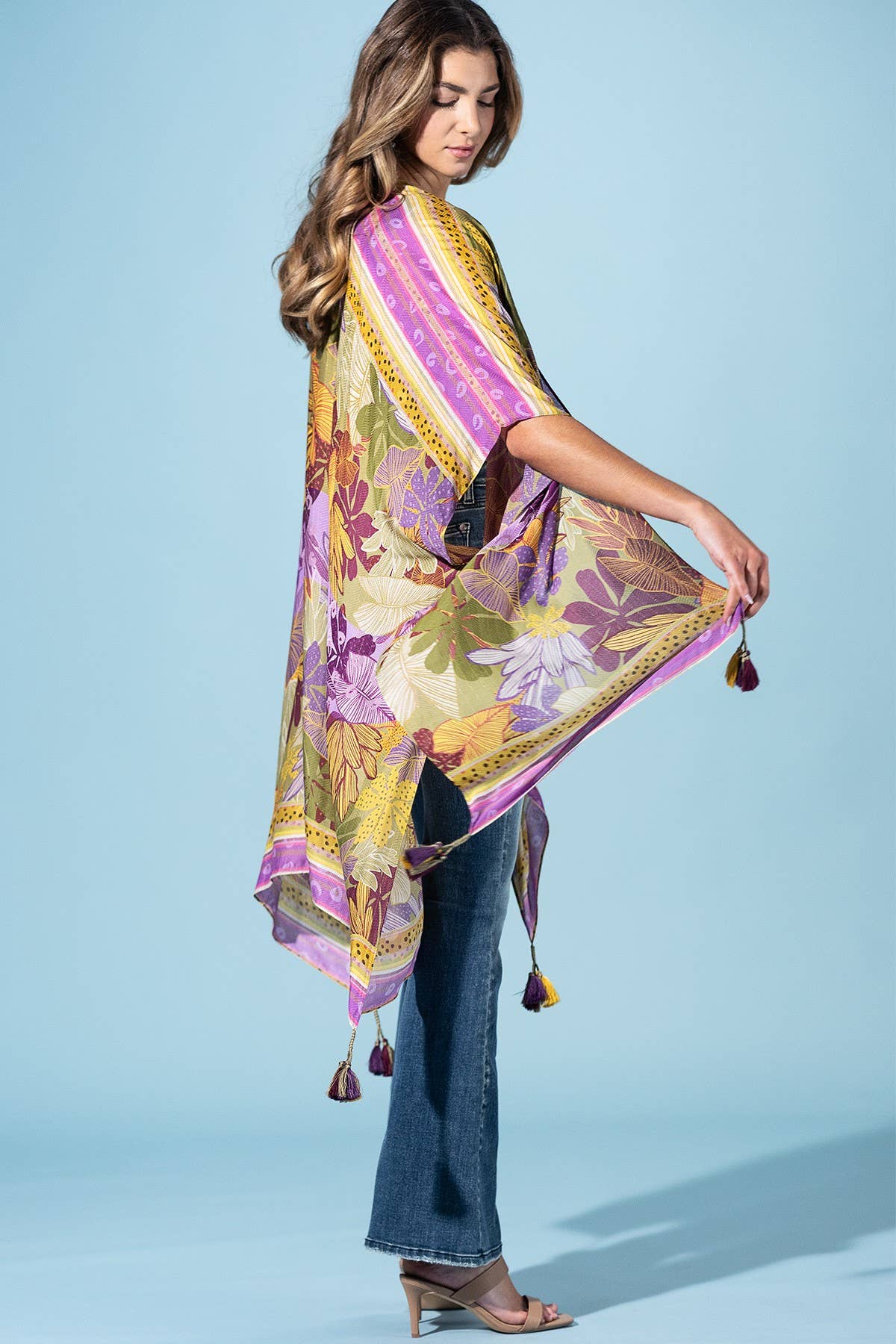Woman holding a colorful floral scarf against a light blue background