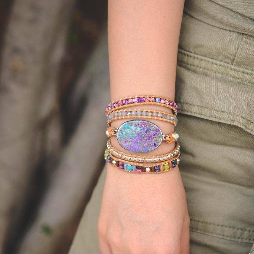 Hand wearing multiple colorful bracelets on a blurred natural background