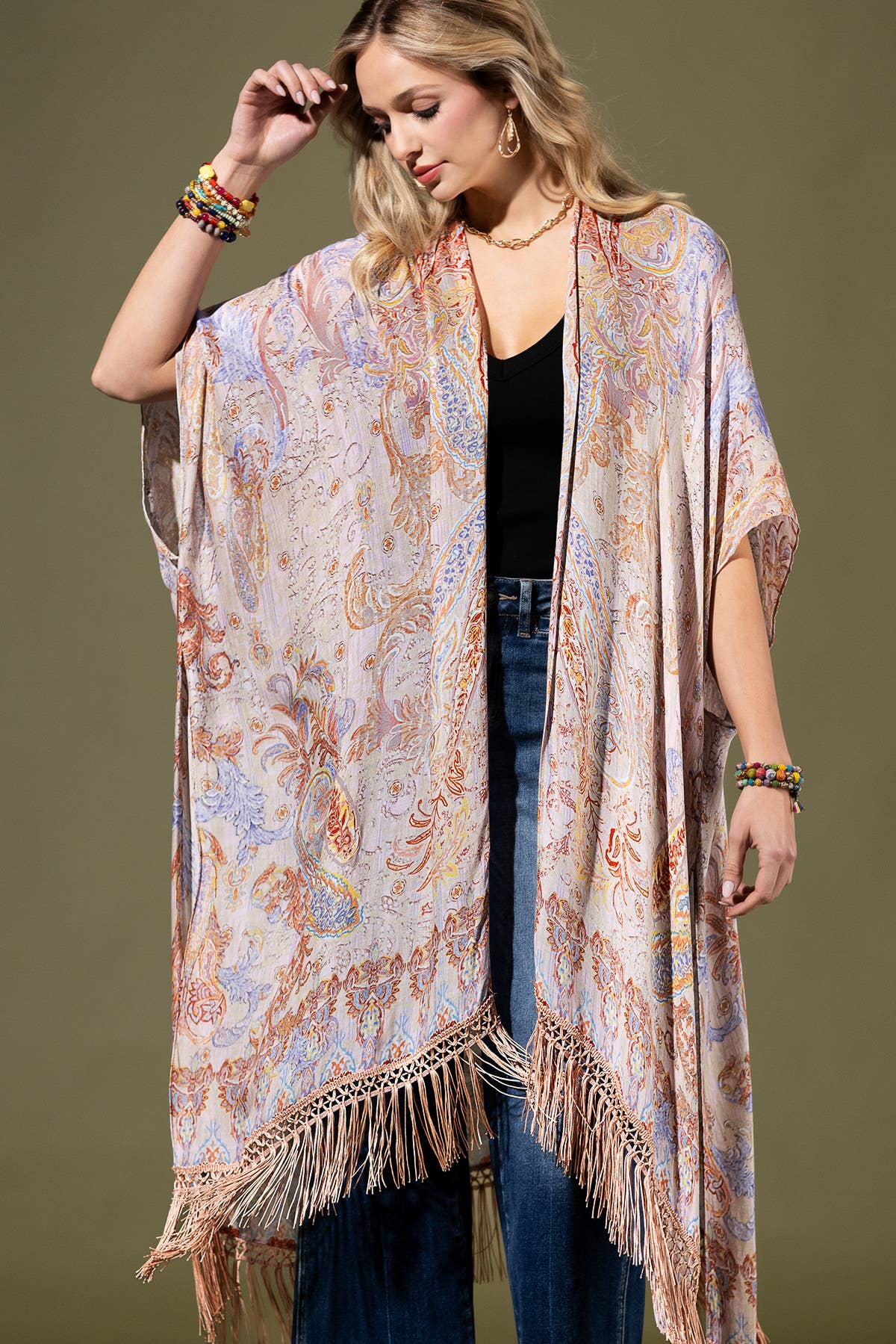 Woman wearing a patterned kimono with fringe details against a brown background