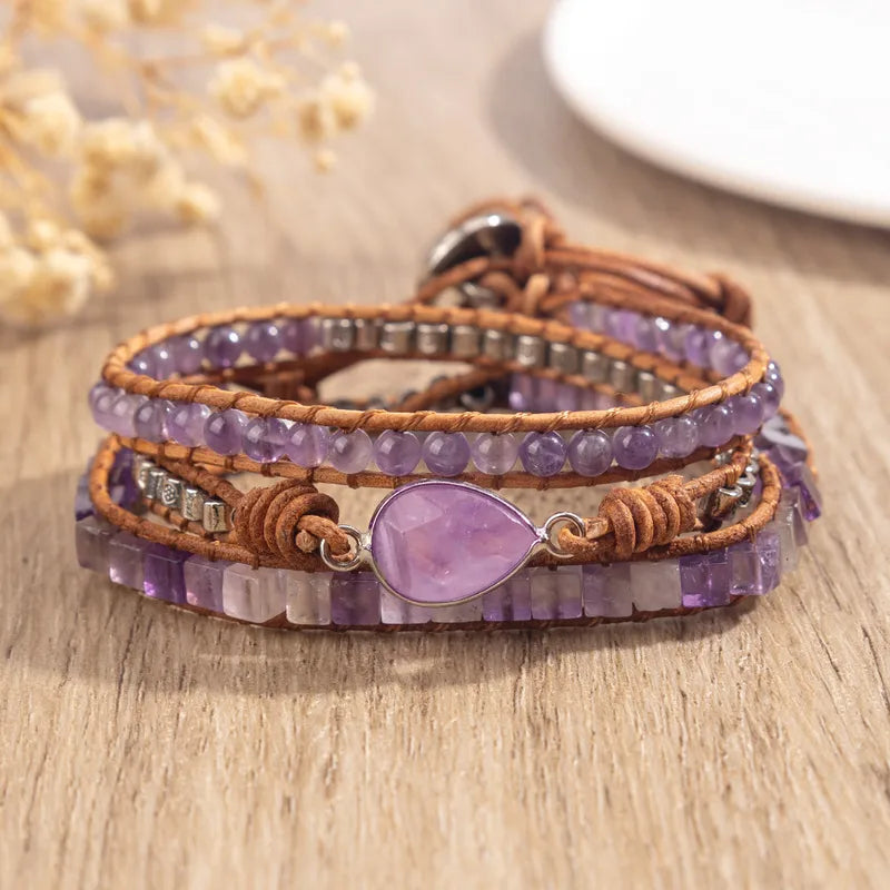 Multistrand bracelet with purple stones and leather wrap on a wooden surface
