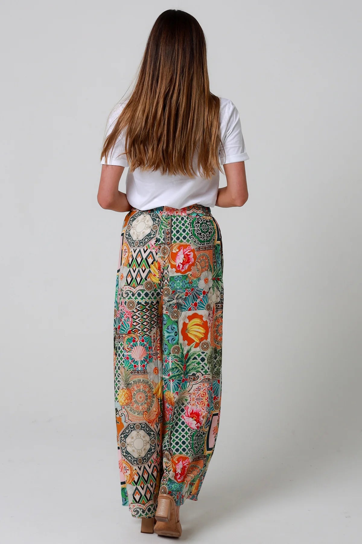 Woman wearing colorful patterned pants on a plain background