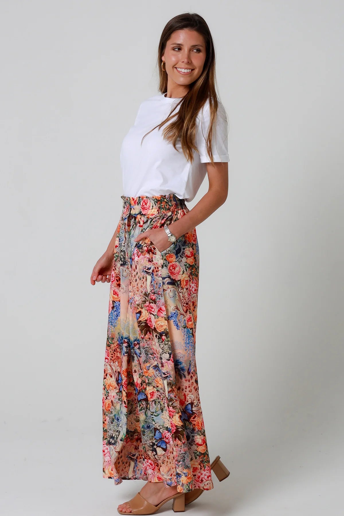 Woman wearing a white top and floral skirt on a plain background