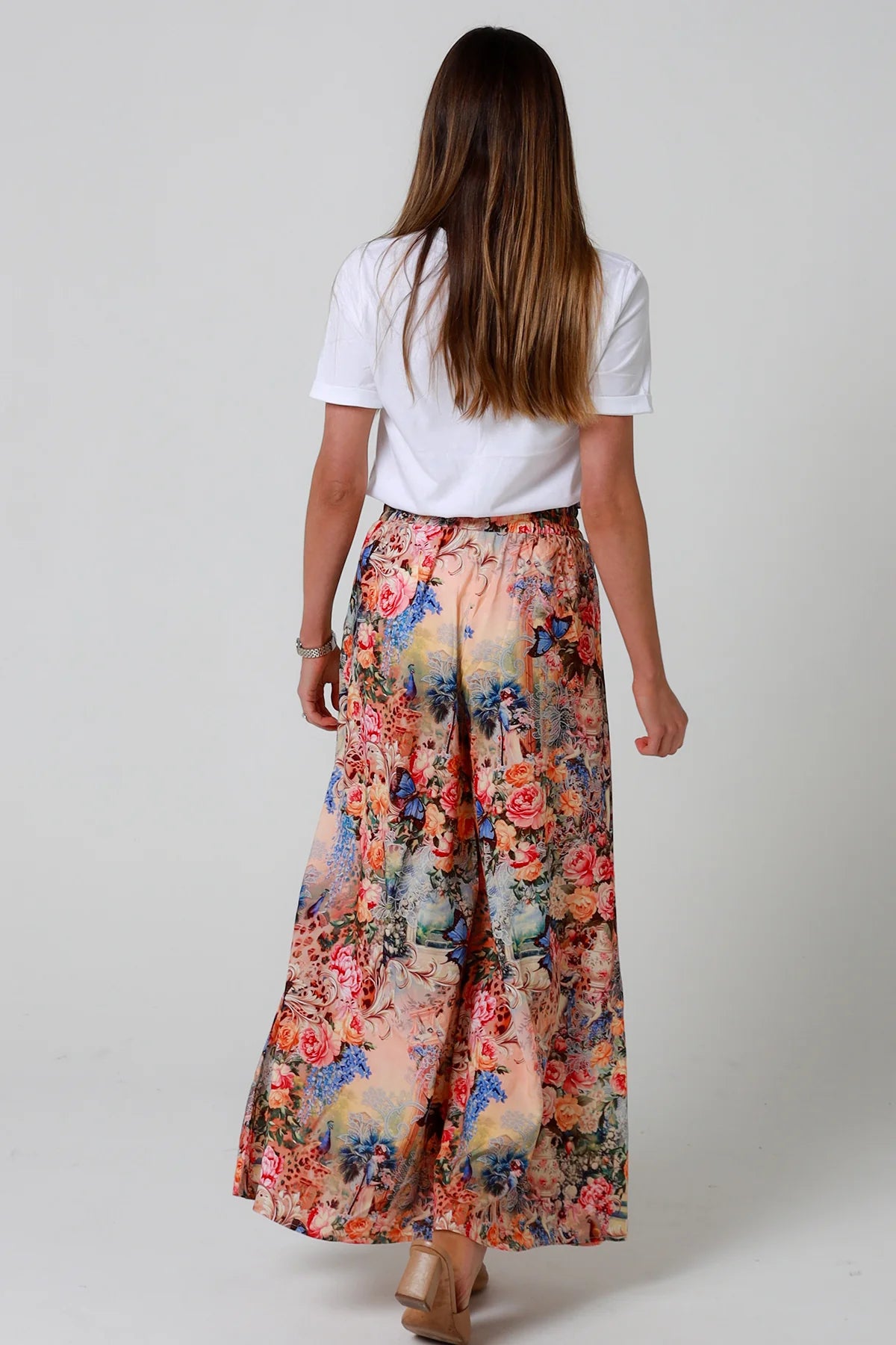 Woman wearing a white t-shirt and floral skirt on a plain background
