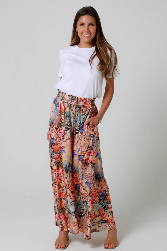 Woman wearing a white top and floral skirt on a plain background