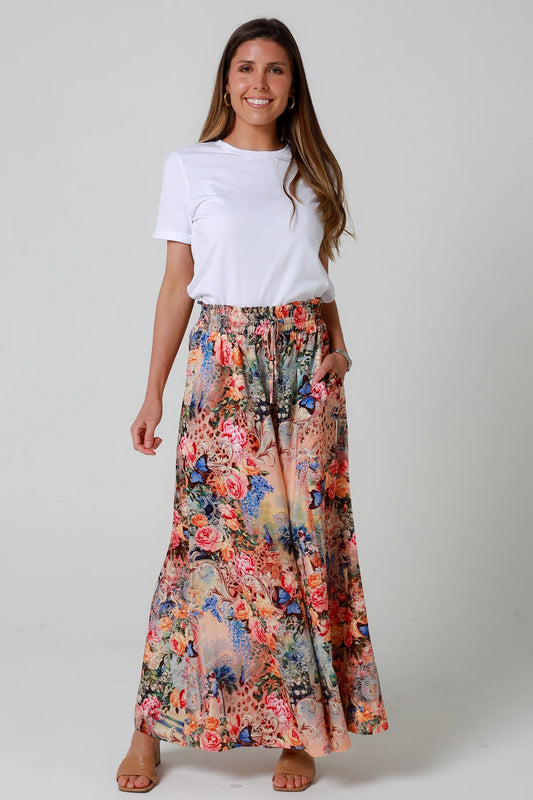Woman wearing a white t-shirt and a colorful floral skirt on a plain background