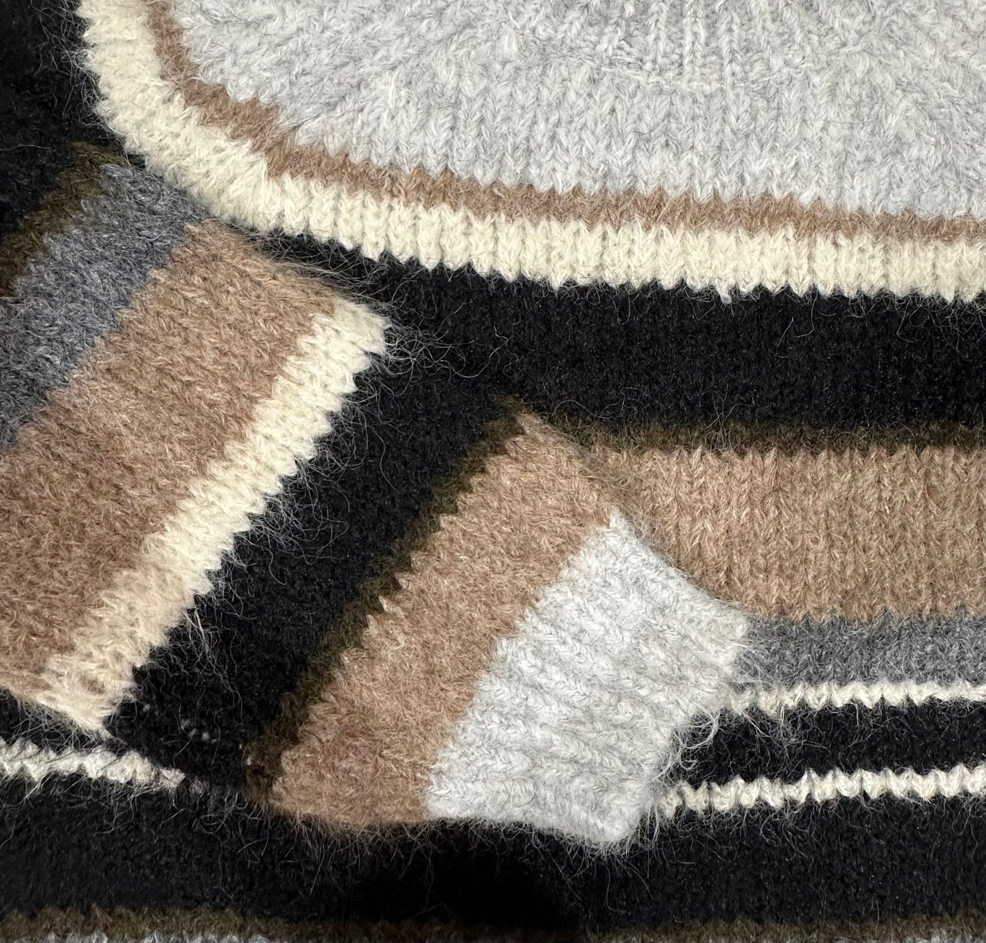 Close-up of a textured fabric with black, brown, and gray stripes.