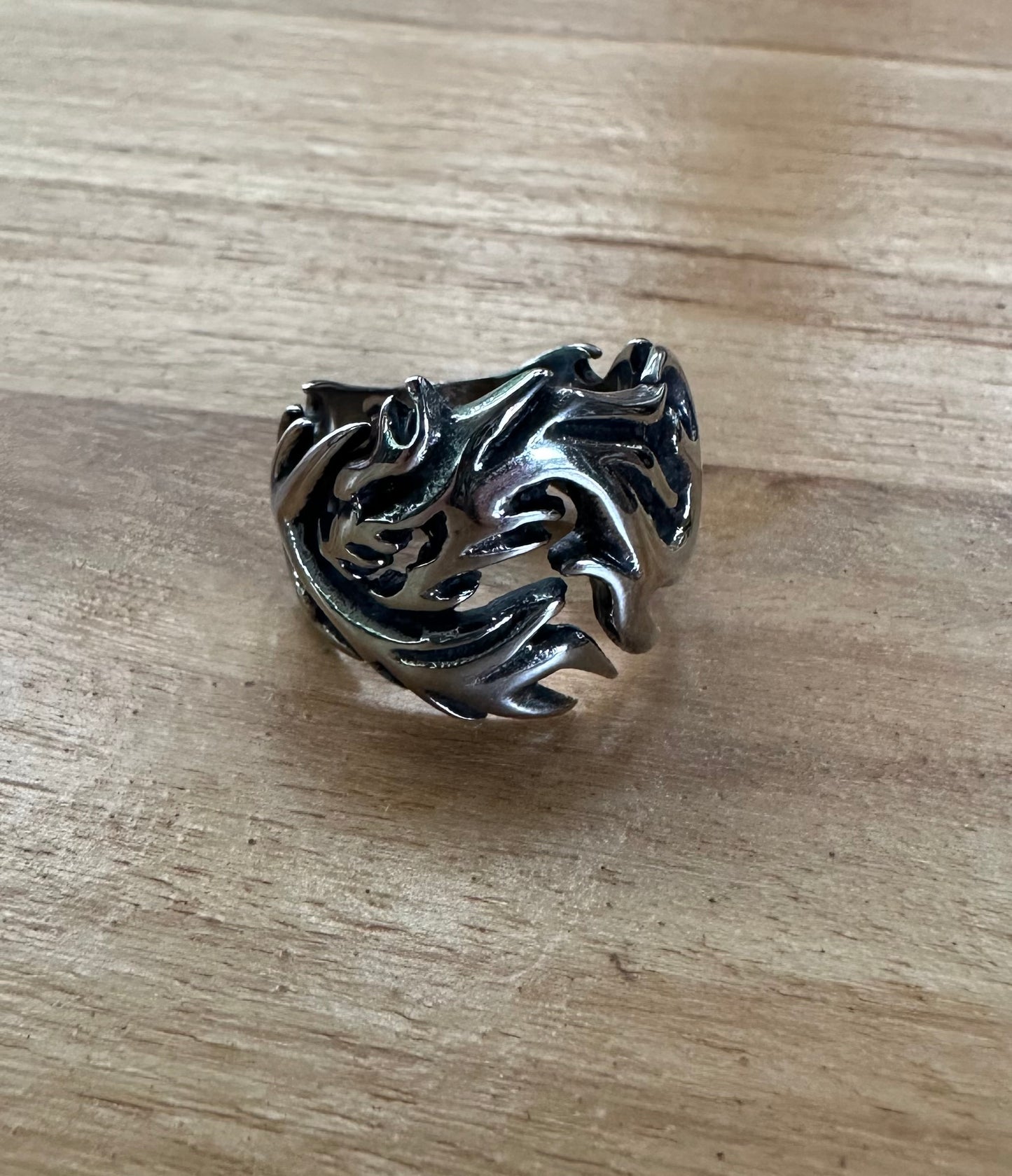 Silver dragon-shaped ring on a wooden surface