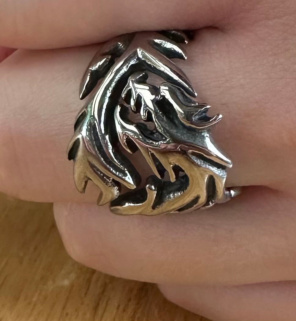 Silver dragon ring on a finger with a wooden background
