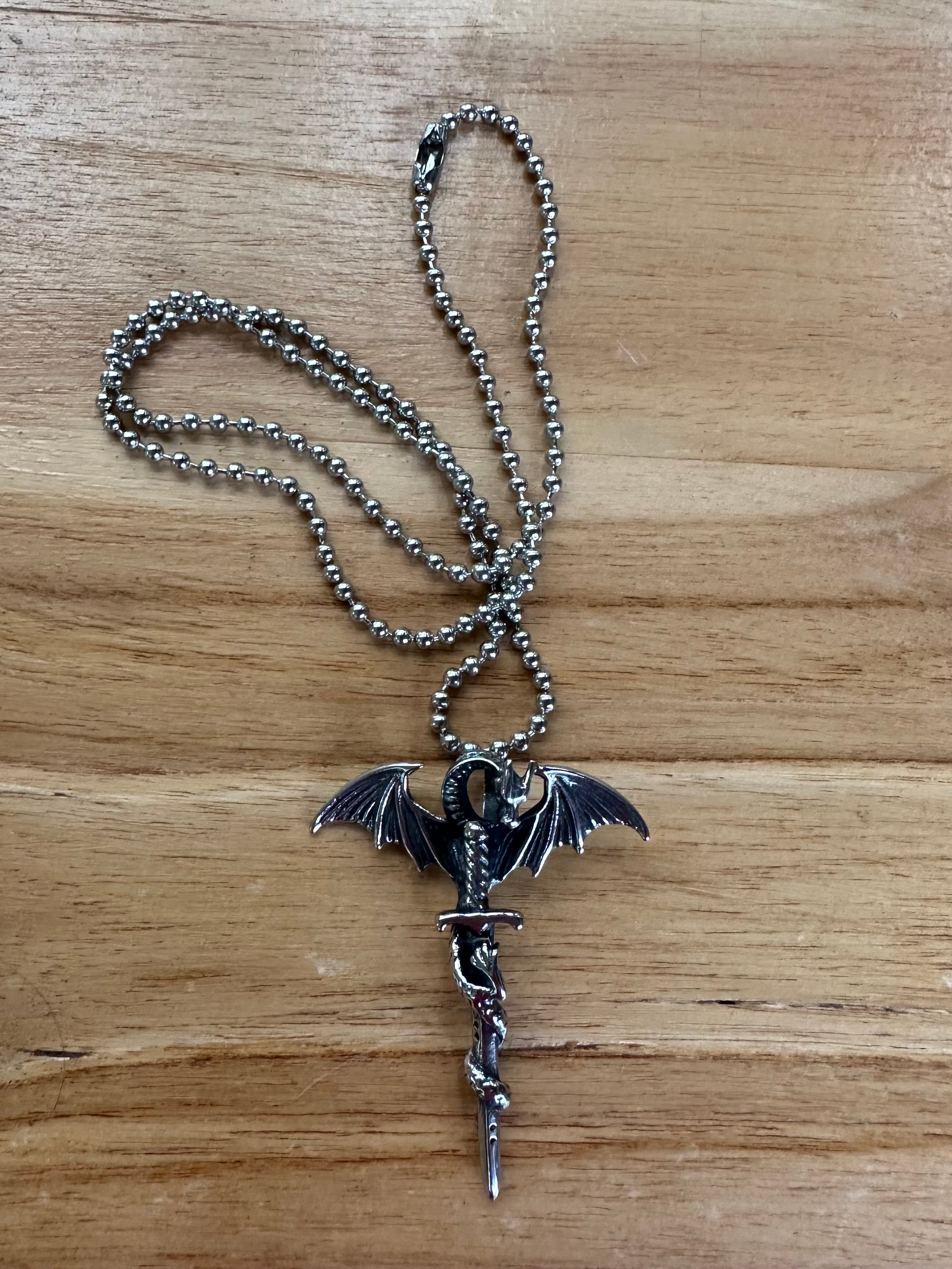 Silver necklace with a dragon pendant on a wooden surface