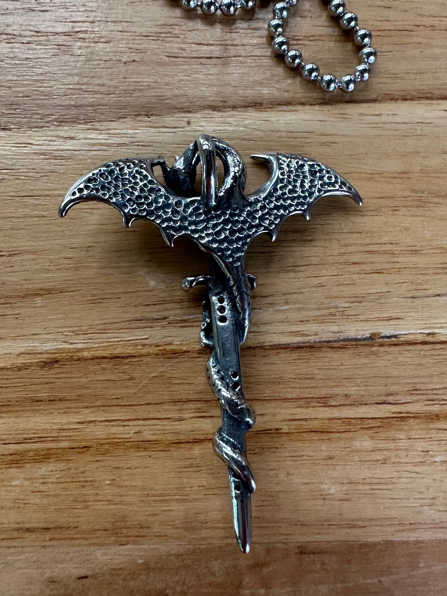 Silver dragon-shaped keychain on a wooden surface