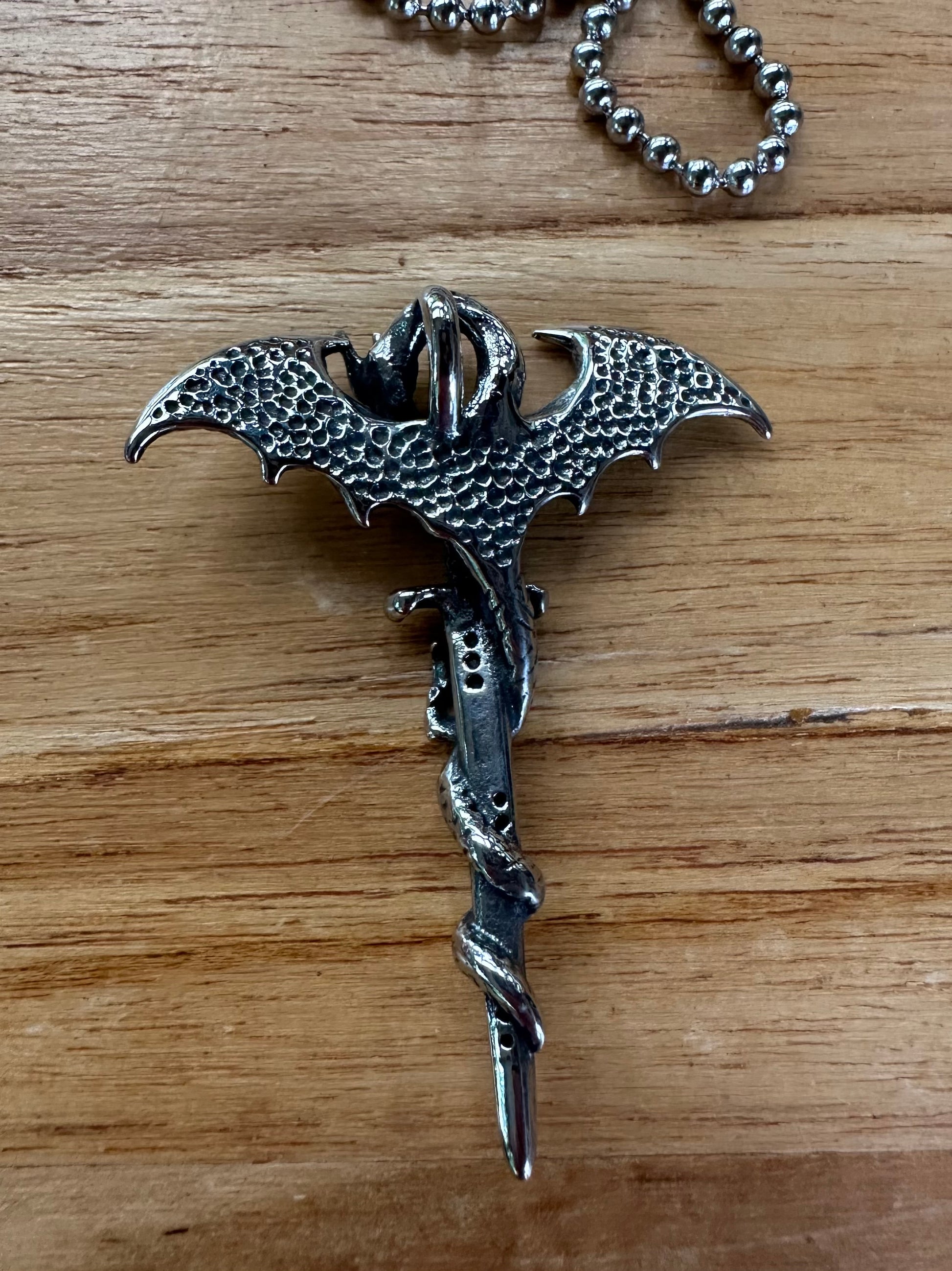 Silver dragon-shaped keychain on a wooden surface