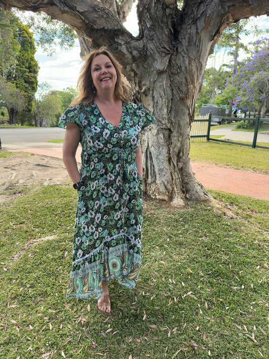 Woman in a floral dress standing in front of a large tree