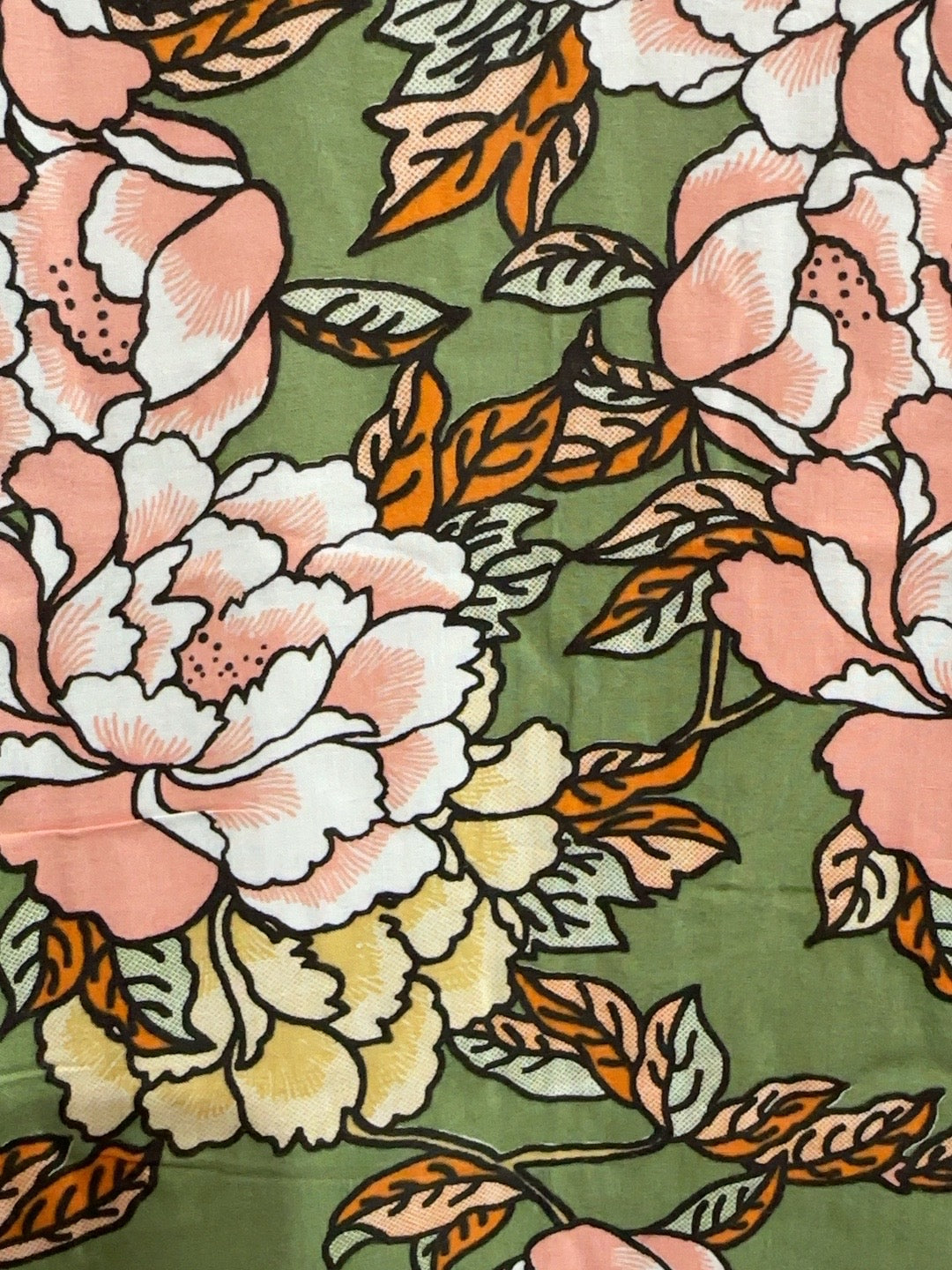 A close-up of a floral fabric print featuring large pink and white peony-like flowers with orange and olive green leaves on an olive green background.