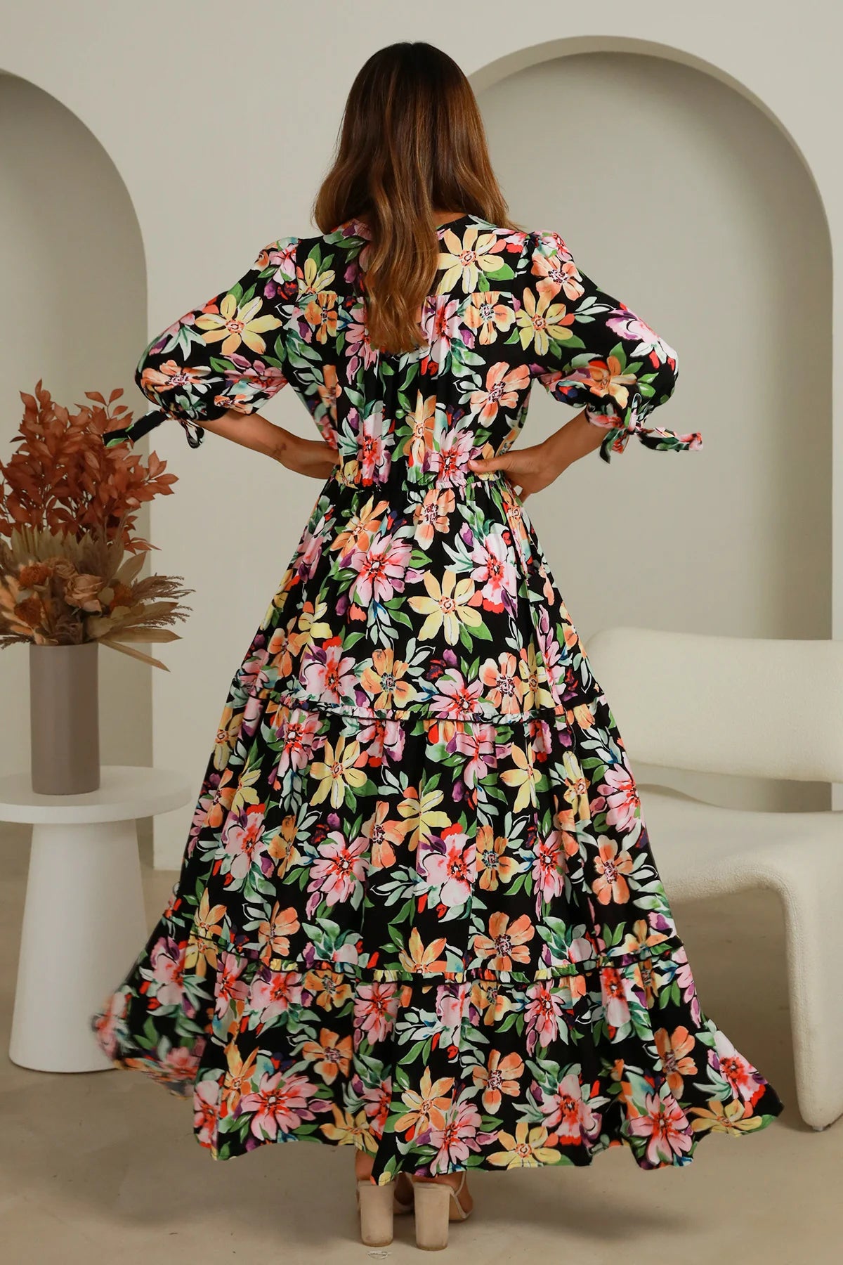 Woman wearing a floral dress in a minimalistic indoor setting