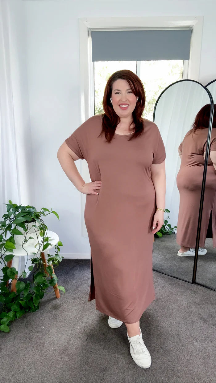 Woman wearing a brown dress standing in front of a mirror.