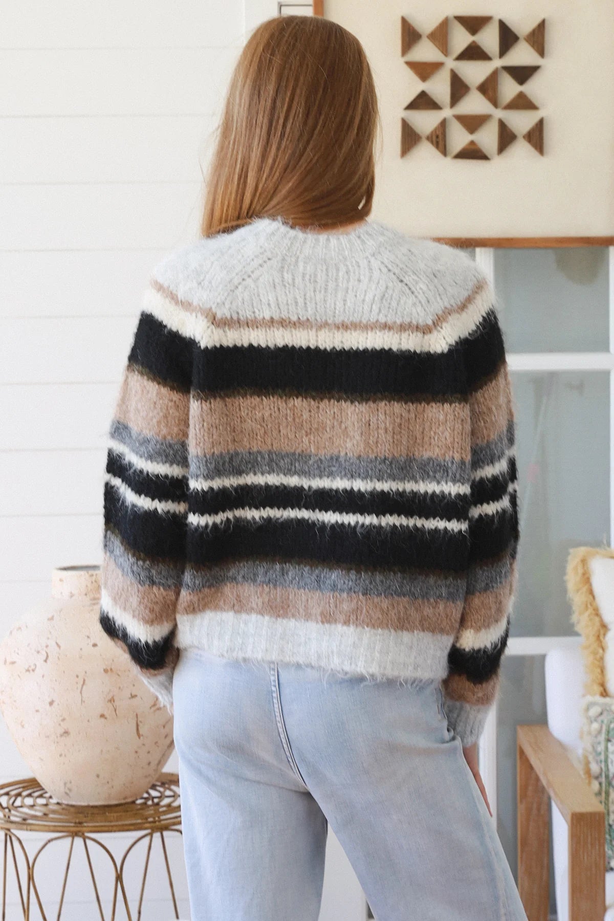 Person wearing a striped sweater in a room with decor elements.