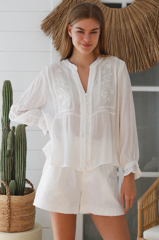 Woman wearing a white dress standing indoors with decorative elements in the background