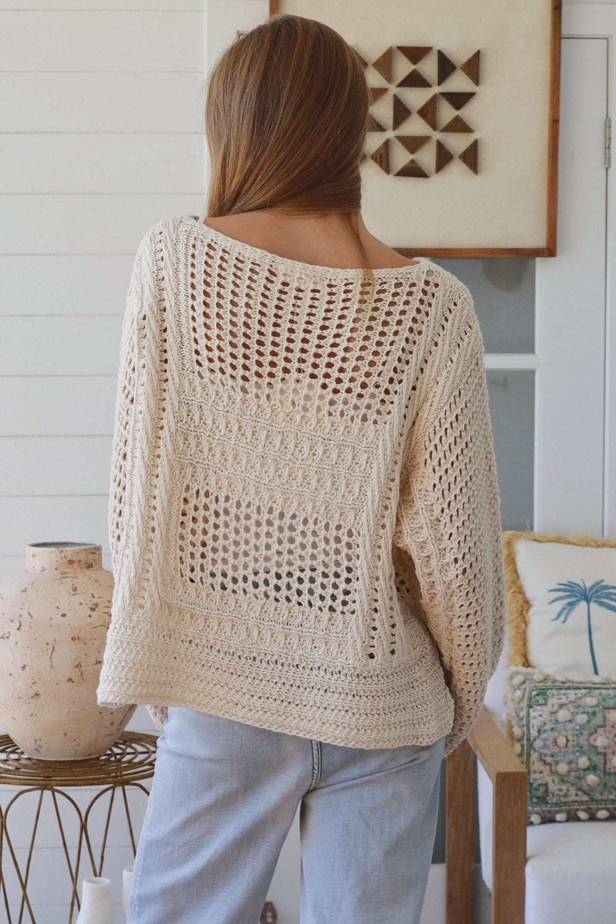 Person wearing a beige crochet sweater in a home setting