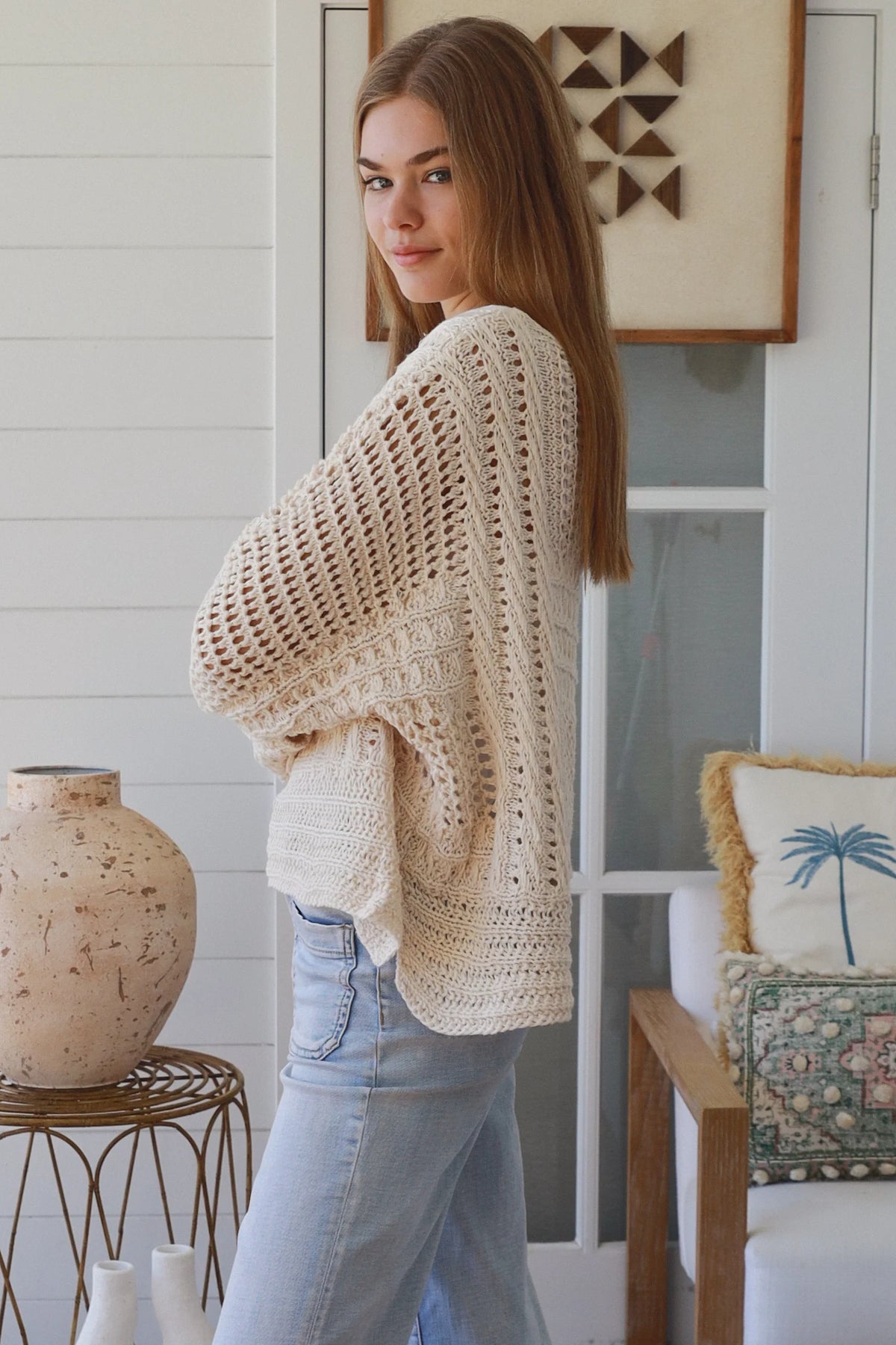 Woman wearing a beige crochet sweater in a home setting