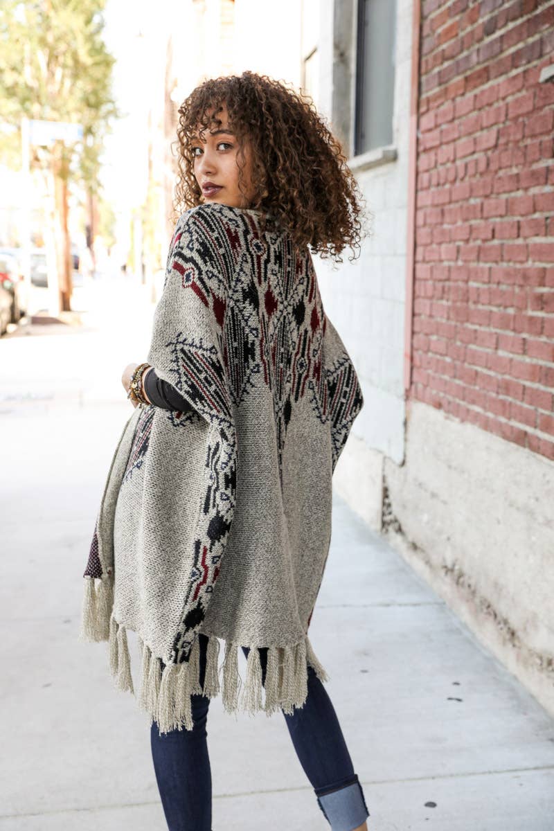 Woman wearing a patterned poncho on a city street.