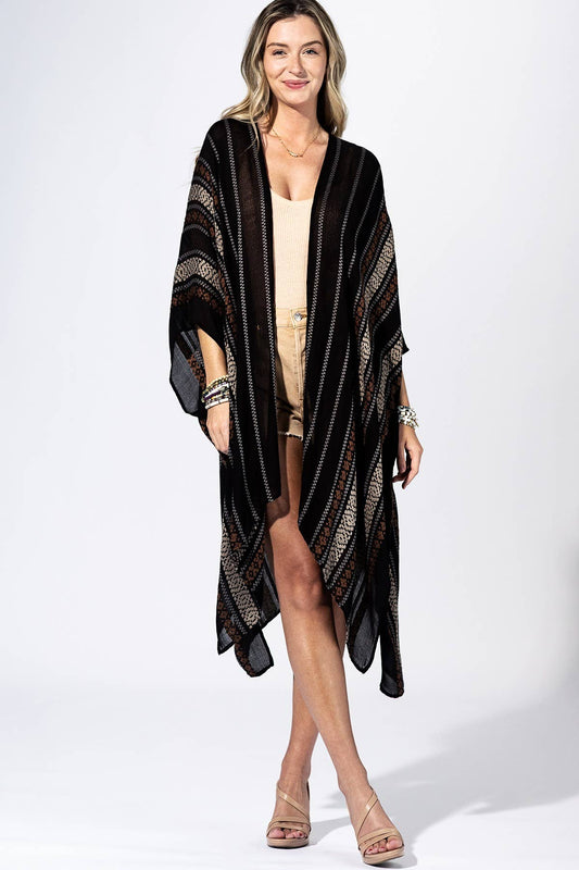 Woman wearing a black and gold patterned kimono over a beige outfit on a white background
