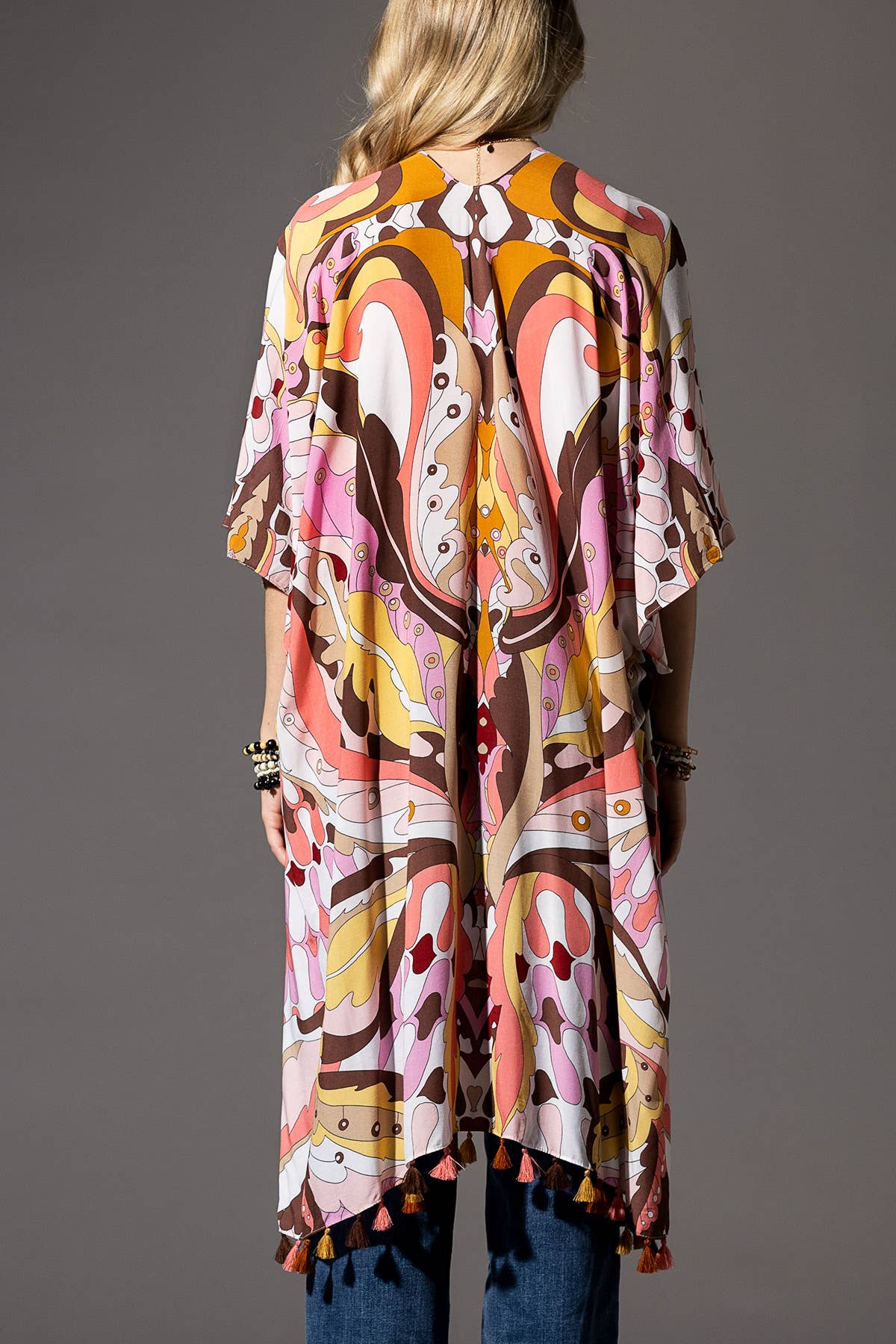 Person wearing a colorful patterned kimono against a gray background