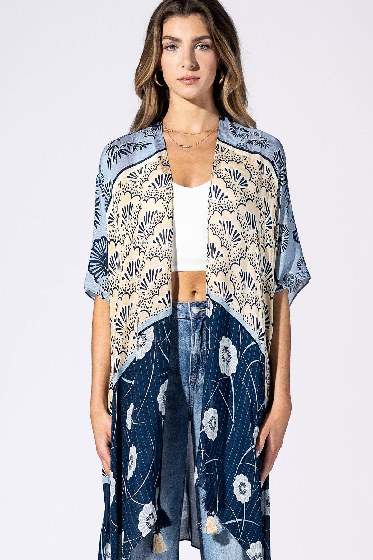 Woman wearing a floral kimono over a white top and jeans on a white background