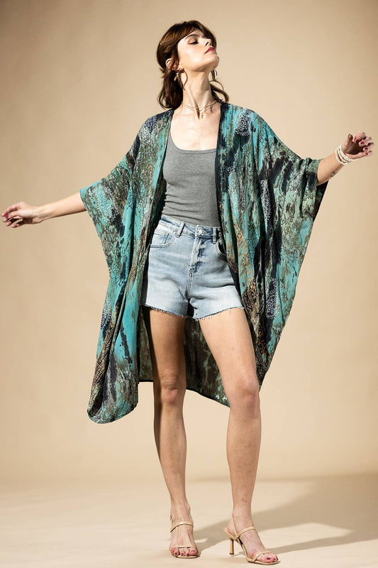 Woman wearing a long, patterned kimono over a casual outfit on a beige background