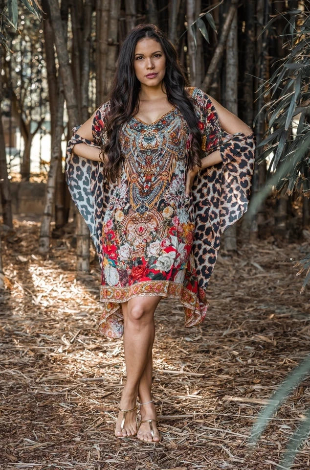 Woman wearing a patterned dress with leopard print sleeves in a forest setting