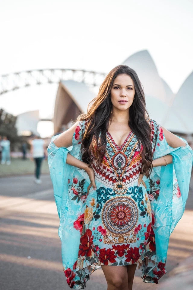 Woman in a colorful dress with floral patterns standing in front of the Sydney Opera House.