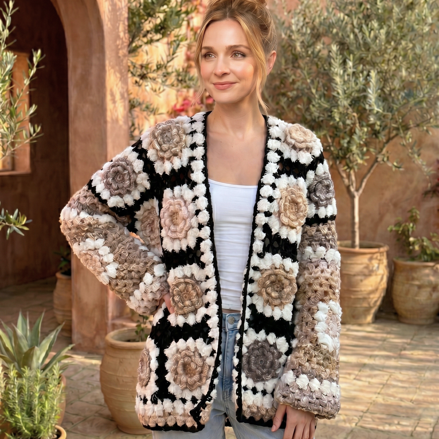 Woman wearing a floral crochet cardigan in an outdoor setting with plants.