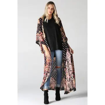 Woman wearing a long floral kimono over a black top and jeans on a white background