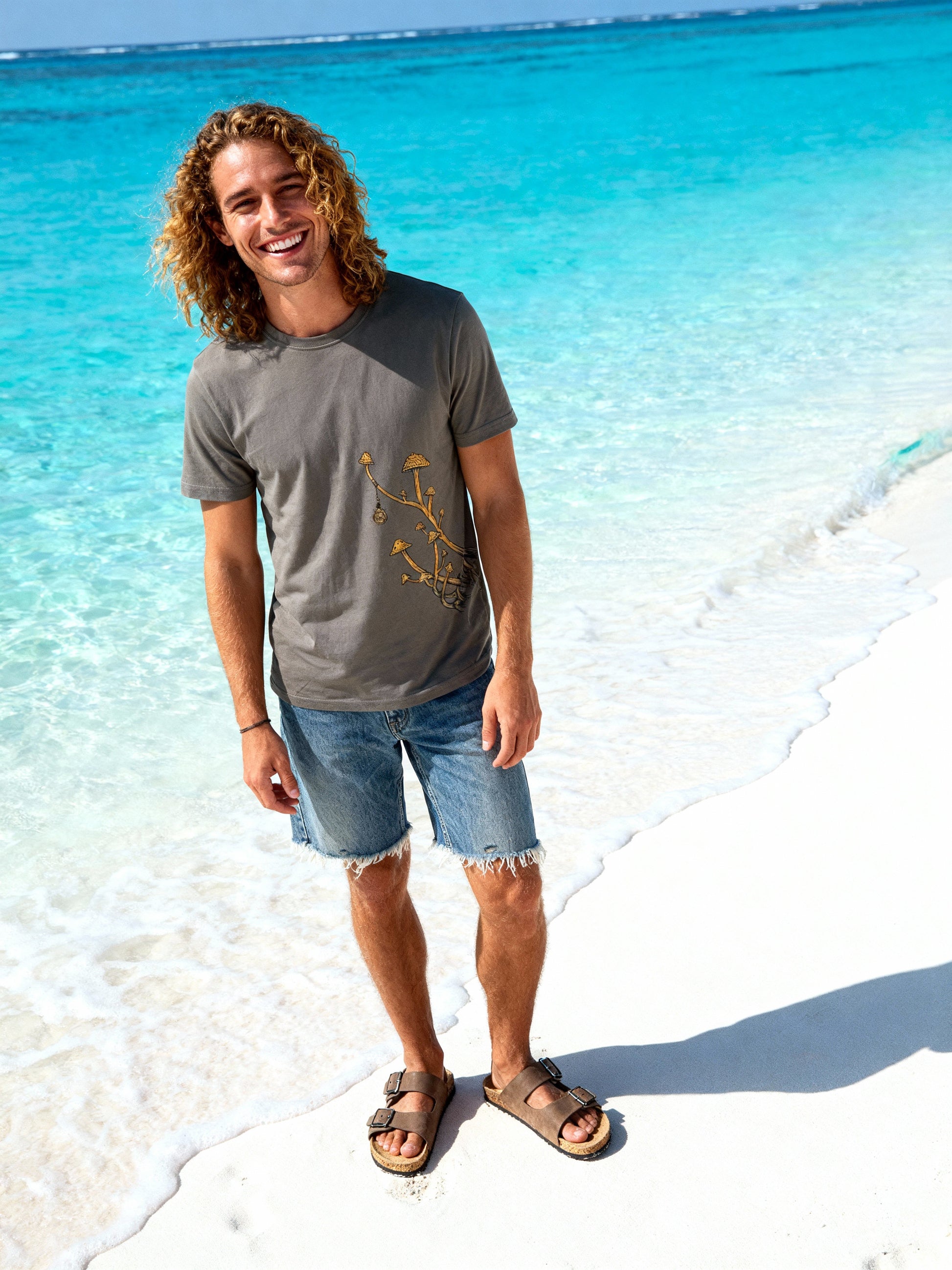 Man standing on a beach with clear blue water and white sand