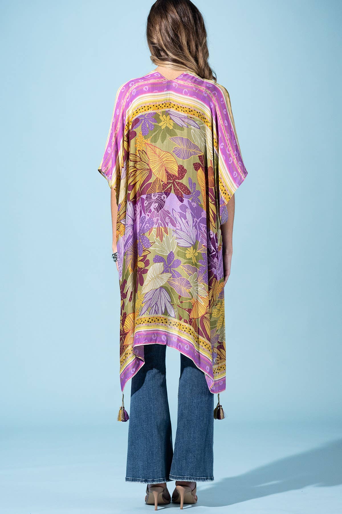 Person wearing a colorful floral kimono against a light blue background