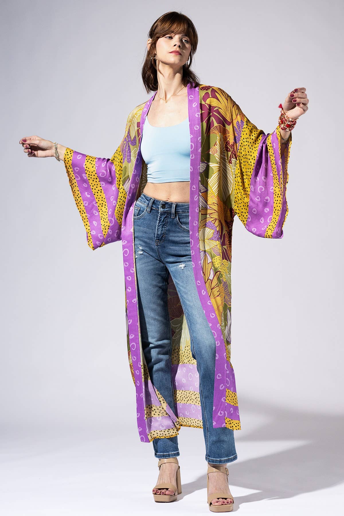 Woman wearing a colorful kimono-style garment with a plain background