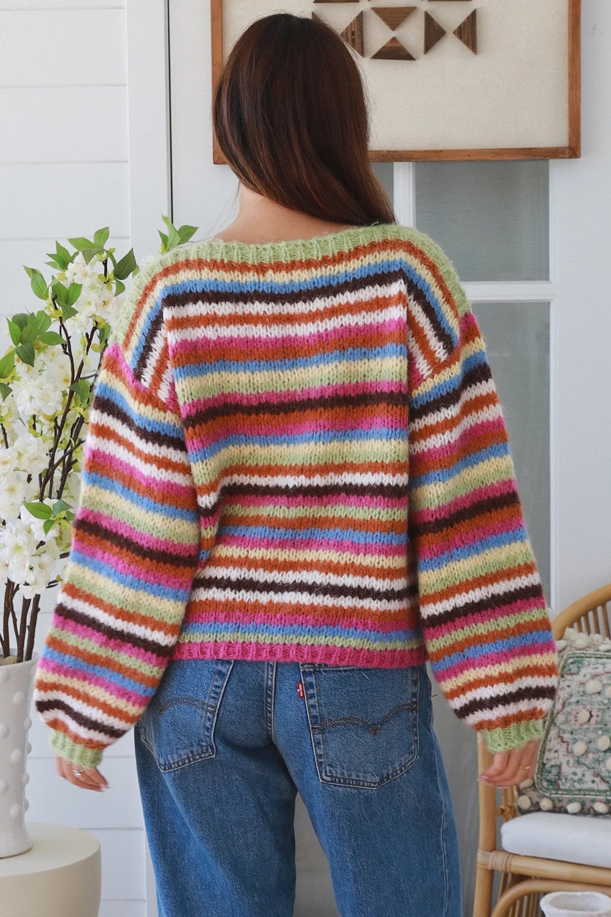 Person wearing a colorful striped sweater in a home setting