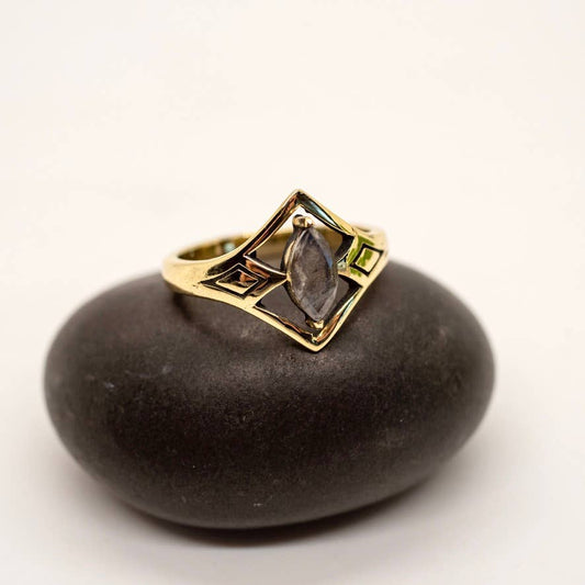 Gold ring with a central stone on a dark stone surface