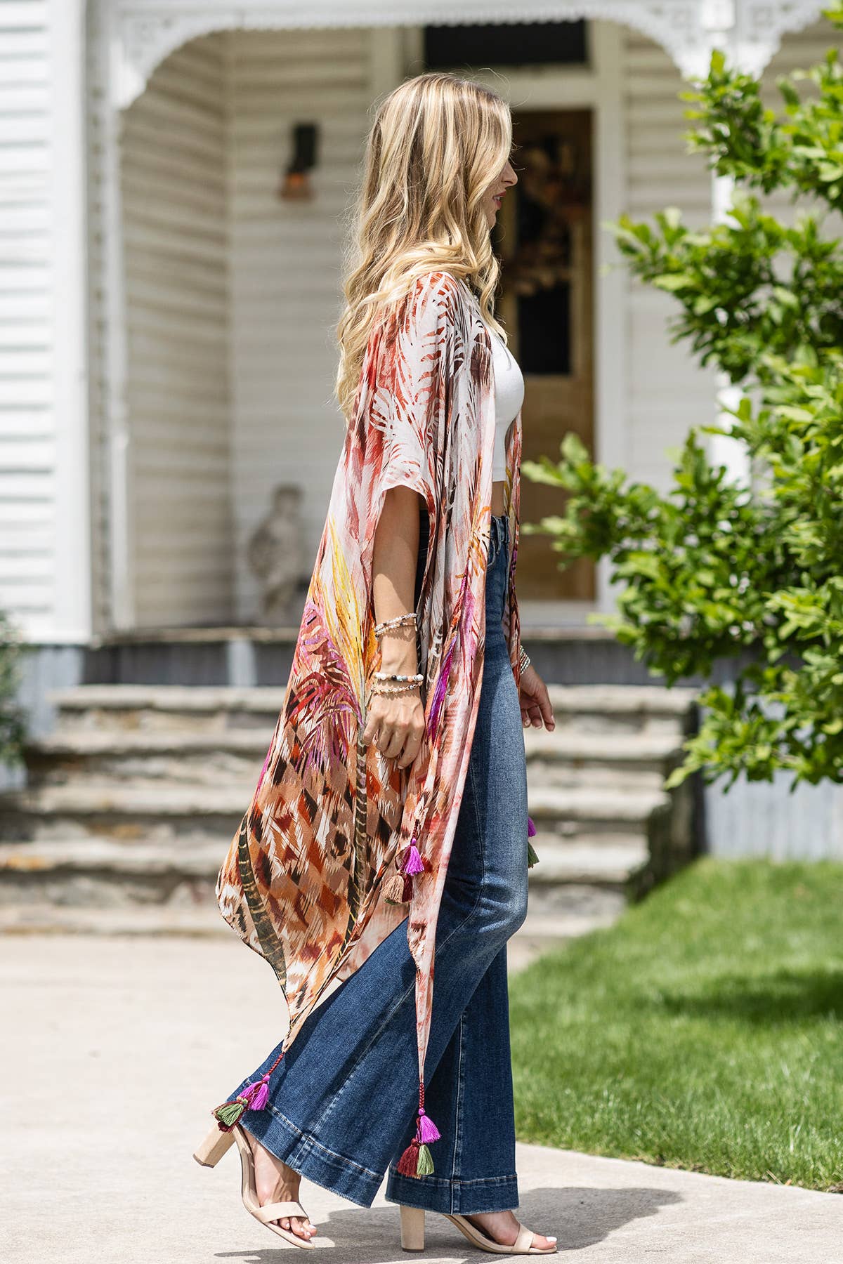 Woman wearing a colorful kimono-style garment in front of a house.