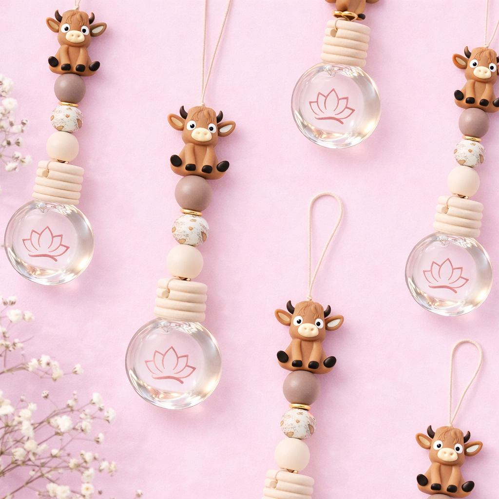 Decorative keychains with cow figures and lotus designs on a pink background