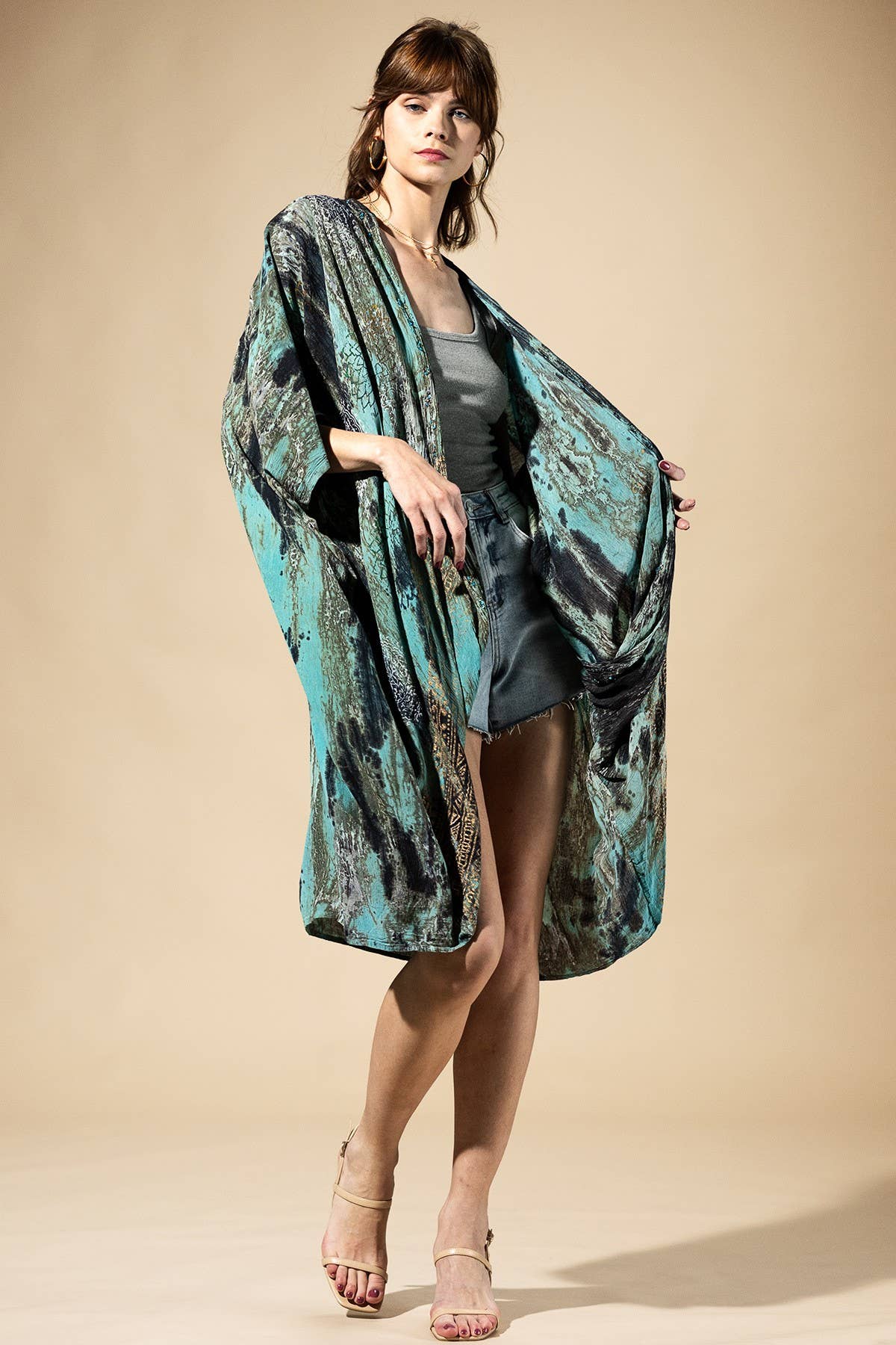 Woman wearing a patterned kimono over a dress on a beige background