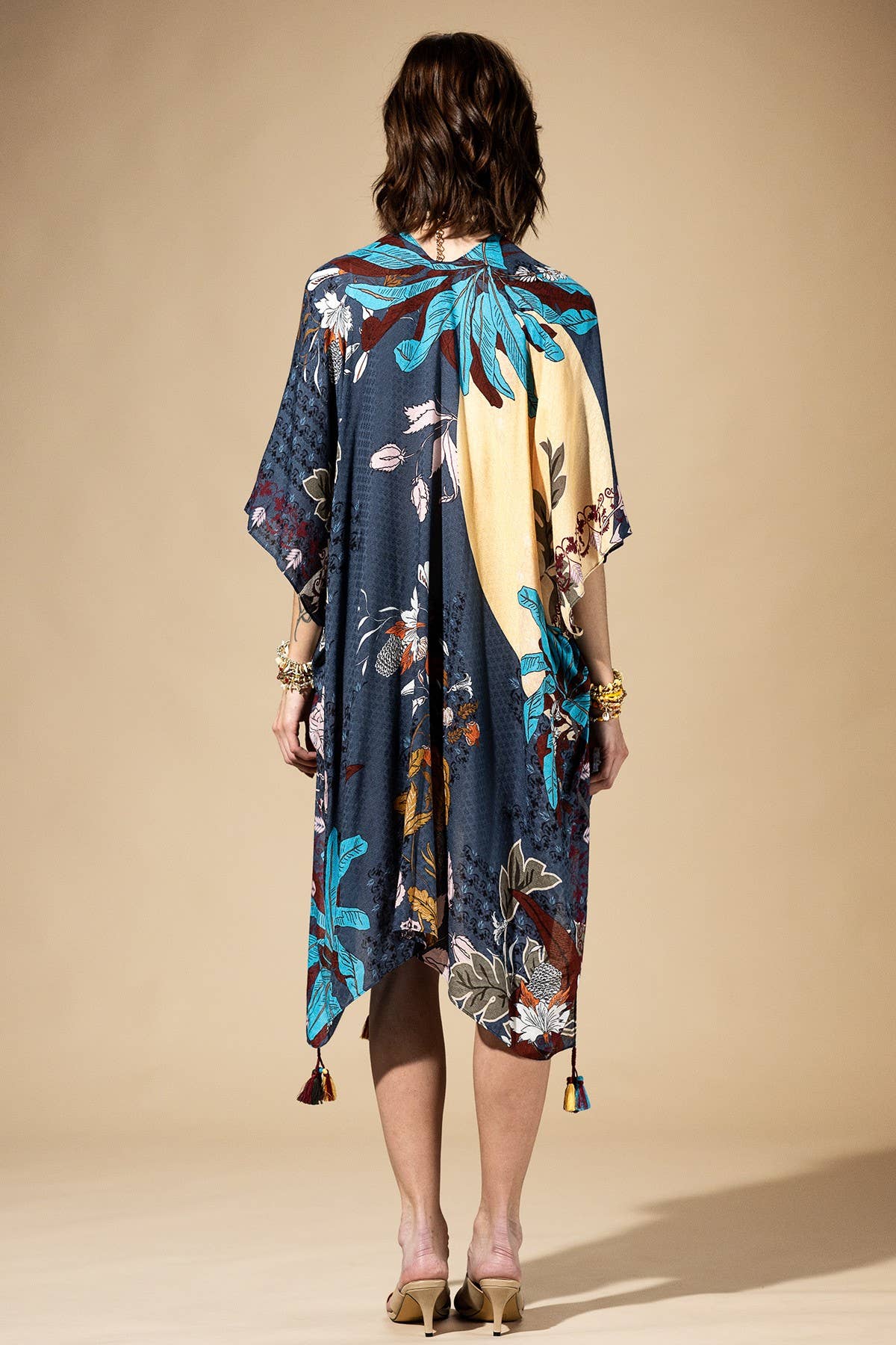 Woman wearing a colorful floral kimono-style dress against a beige background