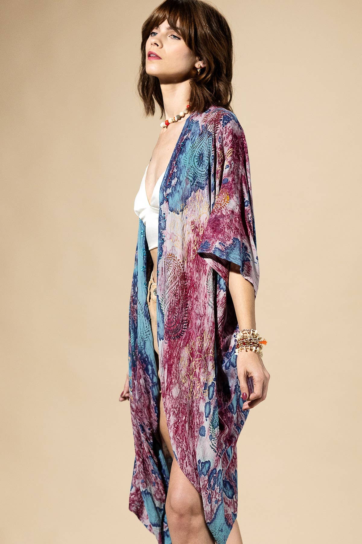 Woman wearing a colorful kimono-style garment against a beige background