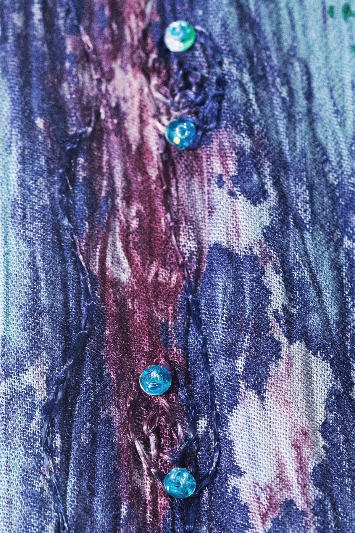 Close-up of a textured fabric with blue buttons on a multicolored background