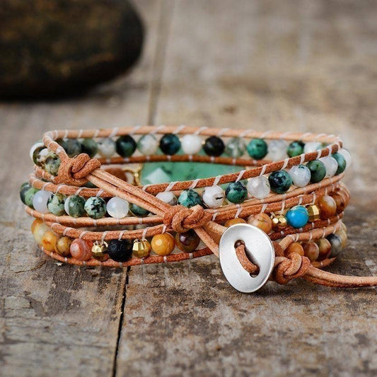 Multistrand beaded bracelet with leather strap on a wooden surface, featuring the brand 'Free Spirit Shop'.