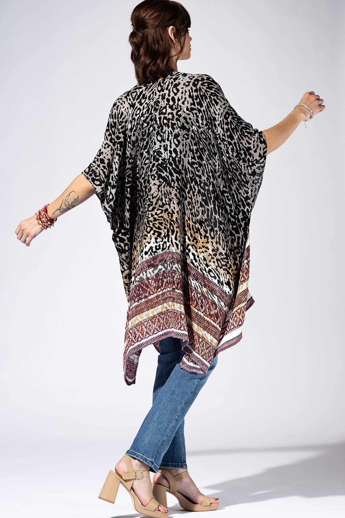 Woman wearing a leopard print kimono with a patterned bottom half on a white background