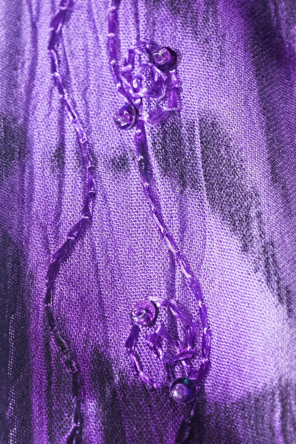 Close-up of a purple decorative item with floral elements on a textured purple background